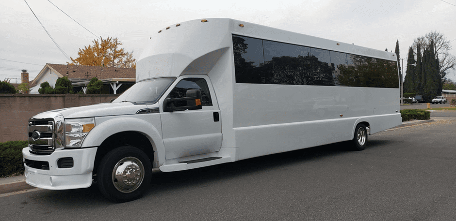 A white party bus parked along the roadside, ready for an event or celebration.